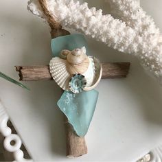 a cross made out of seashells on top of a piece of driftwood