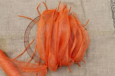 an orange piece of cloth sitting on top of a glass plate next to a carrot