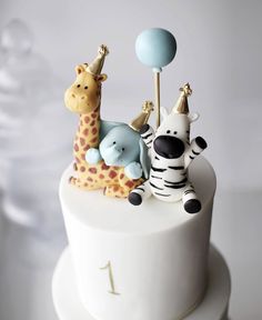 a white cake topped with two giraffes and a zebra