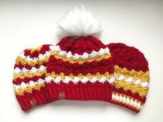 a red and white knitted hat with a pom - pom