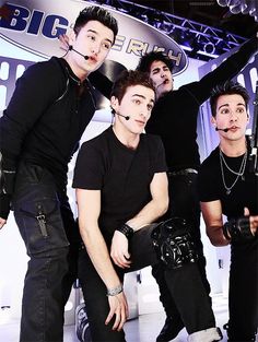 four young men posing for a photo in front of a big fish sign with their hands up