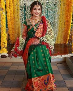 a woman sitting on top of a bench wearing a green and orange sari dress