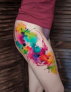 a woman's thigh with colorful paint splattered on it