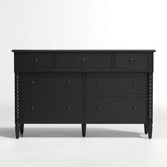 a black dresser with drawers and knobs on the bottom, in front of a white background