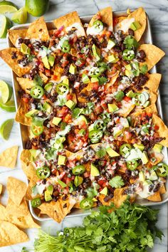 nachos with black beans, cheese and avocado on a platter