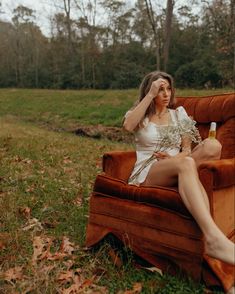 a woman sitting on top of a brown couch next to a forest filled with trees