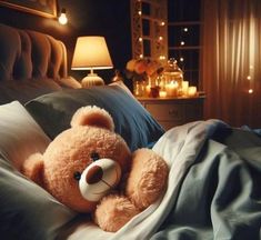 a brown teddy bear laying on top of a bed next to a night stand with candles