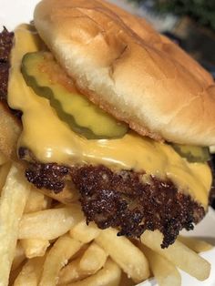 a cheeseburger with pickles and fries on a plate