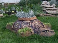 a turtle planter sitting on top of a lush green field