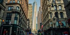 an empty city street with tall buildings in the backgrouns and people walking on the sidewalk