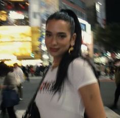 a woman is walking down the street with her hand on her hip and looking at the camera