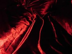 a bed covered in red sheets and pillows