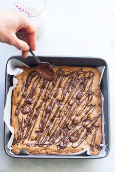 a person is spreading chocolate on top of a baked cookie in a pan with a spoon