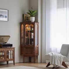 a living room scene with focus on the corner cabinet and chair in the foreground