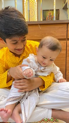 a young man holding a baby in his lap