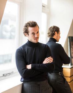 two men standing in front of a window with their arms crossed