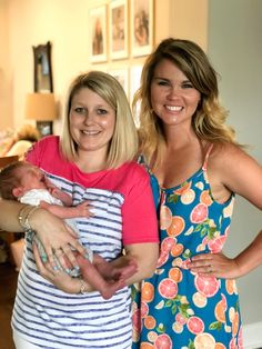 two women standing next to each other holding a baby