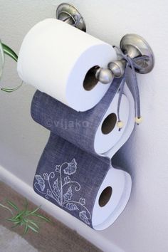 two rolls of toilet paper are hanging on the wall next to a vase with flowers