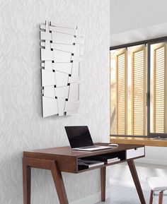 a laptop computer sitting on top of a wooden desk in front of a wall mounted mirror