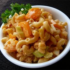 a white bowl filled with macaroni salad on top of a black countertop