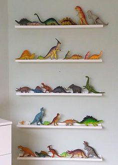 there are many toy dinosaurs on the shelves