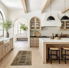 a kitchen with wooden floors and white walls, along with an area rug on the floor