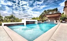 an outdoor swimming pool surrounded by trees and shrubs