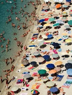 many people are laying on the beach with their umbrellas in the water and sunbathers