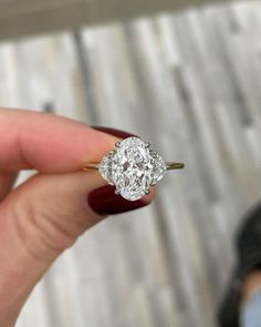 a close up of a person's hand holding a ring with a diamond in it