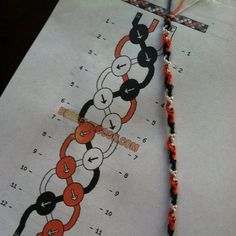 an orange and black chain is attached to a white piece of paper with red thread