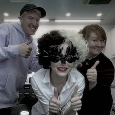 three people are posing for the camera with one woman wearing a black mask and another man in a white shirt