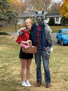 a woman standing next to a man dressed as a wolf and holding a basket in front of her