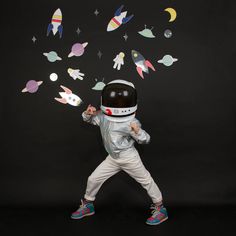 a little boy in an astronaut suit throwing paper rockets into the air