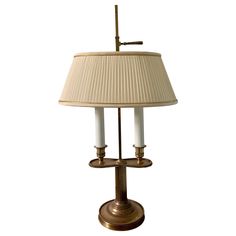 a table lamp with two white candles on it and a beige shade over the lampshade