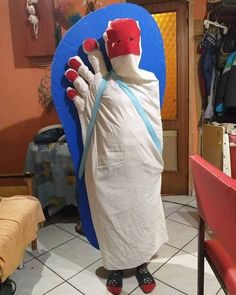 a person dressed in a costume standing next to a blue circle with red hands and feet