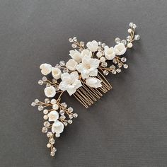 a bridal hair comb with flowers and pearls on the headpiece is laying on a gray surface