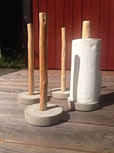 three white vases sitting on top of a wooden table next to two wood poles