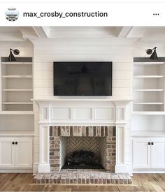 a living room with white bookcases and a tv mounted on the wall above a fireplace