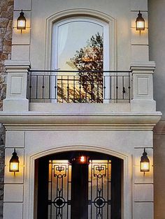 the front entrance to a house with wrought iron railings and lanterns on either side