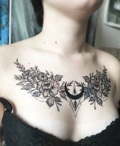 a woman with flowers and crescent tattoo on her chest