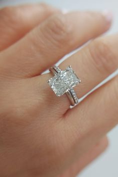 a woman's hand with a diamond ring on top of her finger and an engagement band