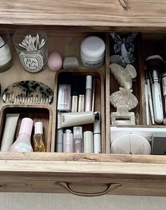 an open drawer with various items in it and on the bottom shelf is a mirror