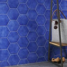 a blue tiled wall with a white bag and shoes on the shelf next to it