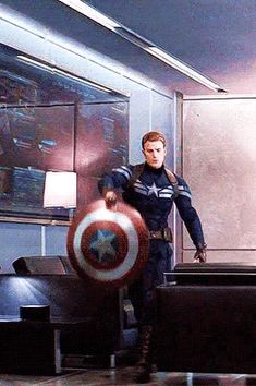 captain america is standing in the middle of a room