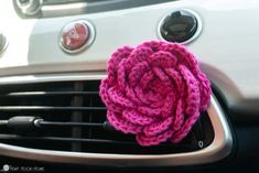 a close up of a car air vent with a pink flower on the front grill