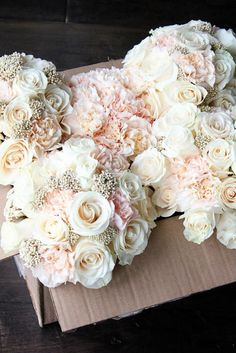 a bouquet of white and pink flowers sitting on top of a cardboard box