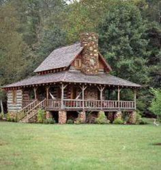 a log cabin sits in the middle of a grassy area with trees and shrubs surrounding it