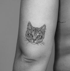 a black and white photo of a cat's face on the left side of his arm