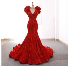 a red dress is on display in a room with a white wall and grey carpet