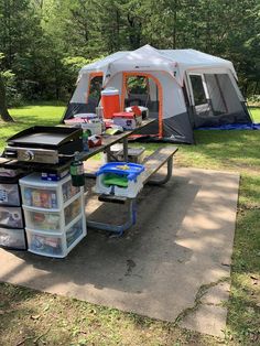 a tent is set up in the middle of a field with coolers on it